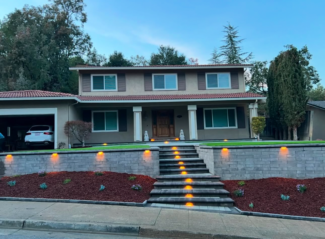 Front yard with retaining wall, steps, and landscape lighting