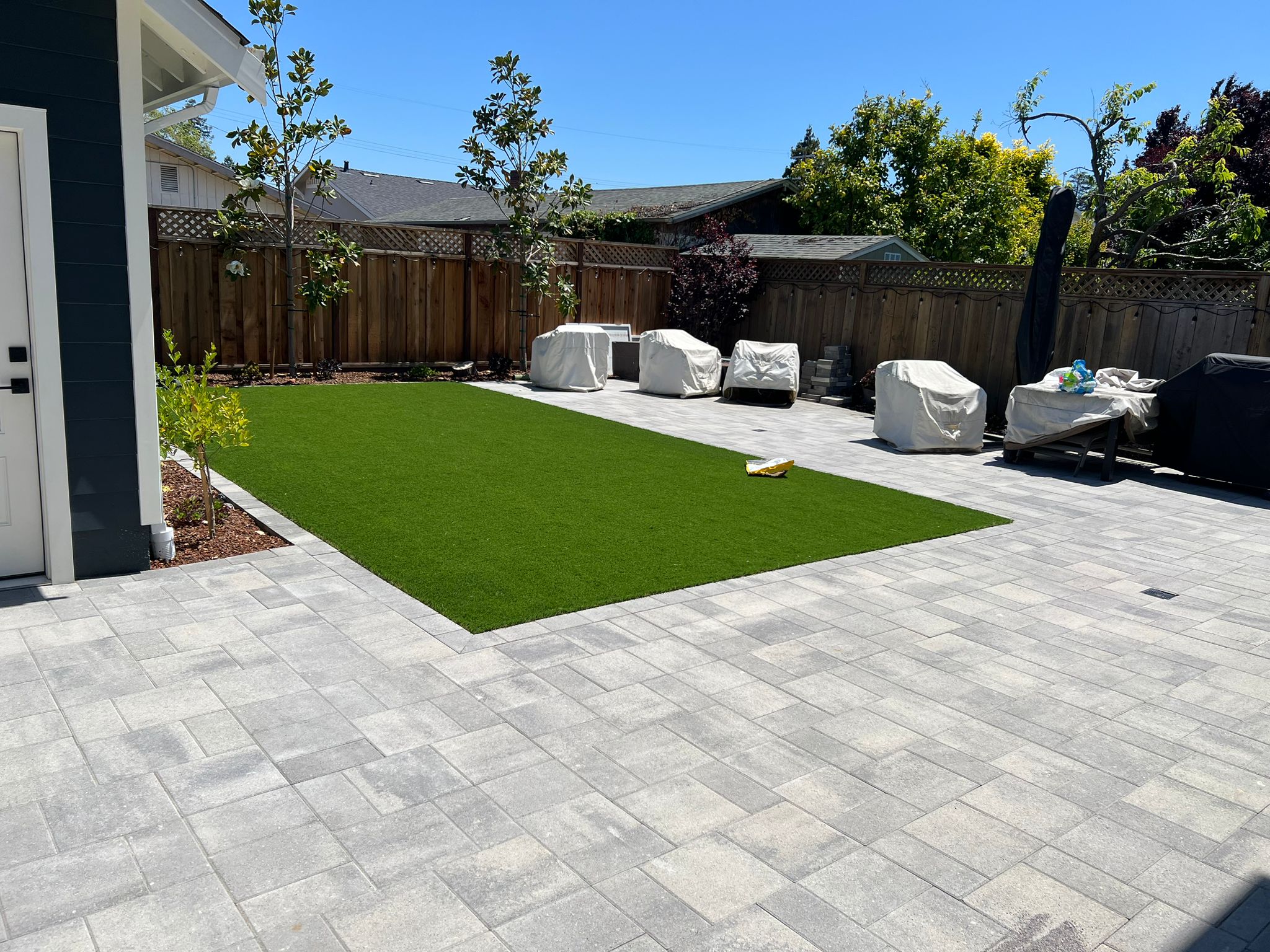 Backyard patio with artificial turf and covered furniture